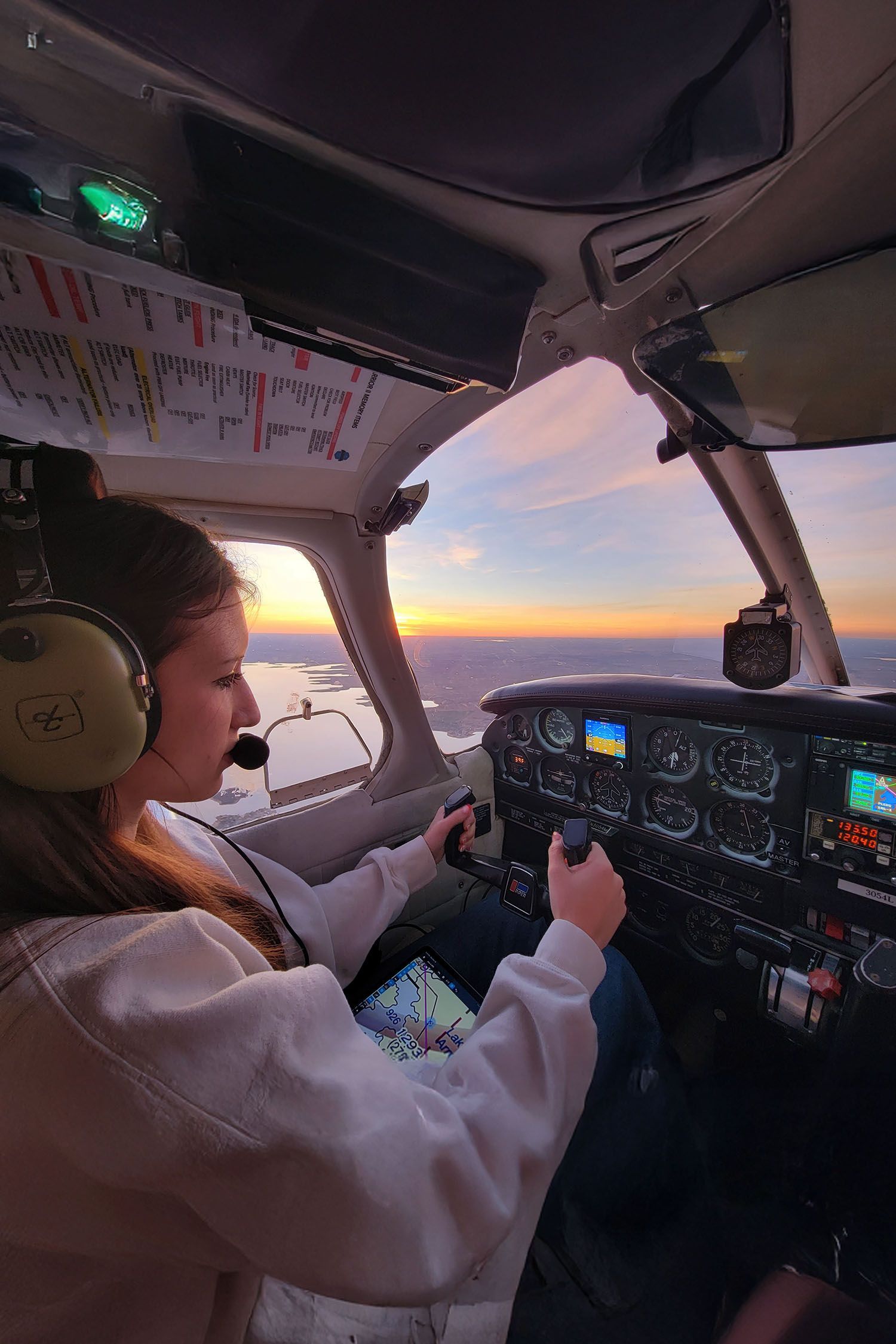 Cockpit interior at sunset showing instrument panel and flight checklist.