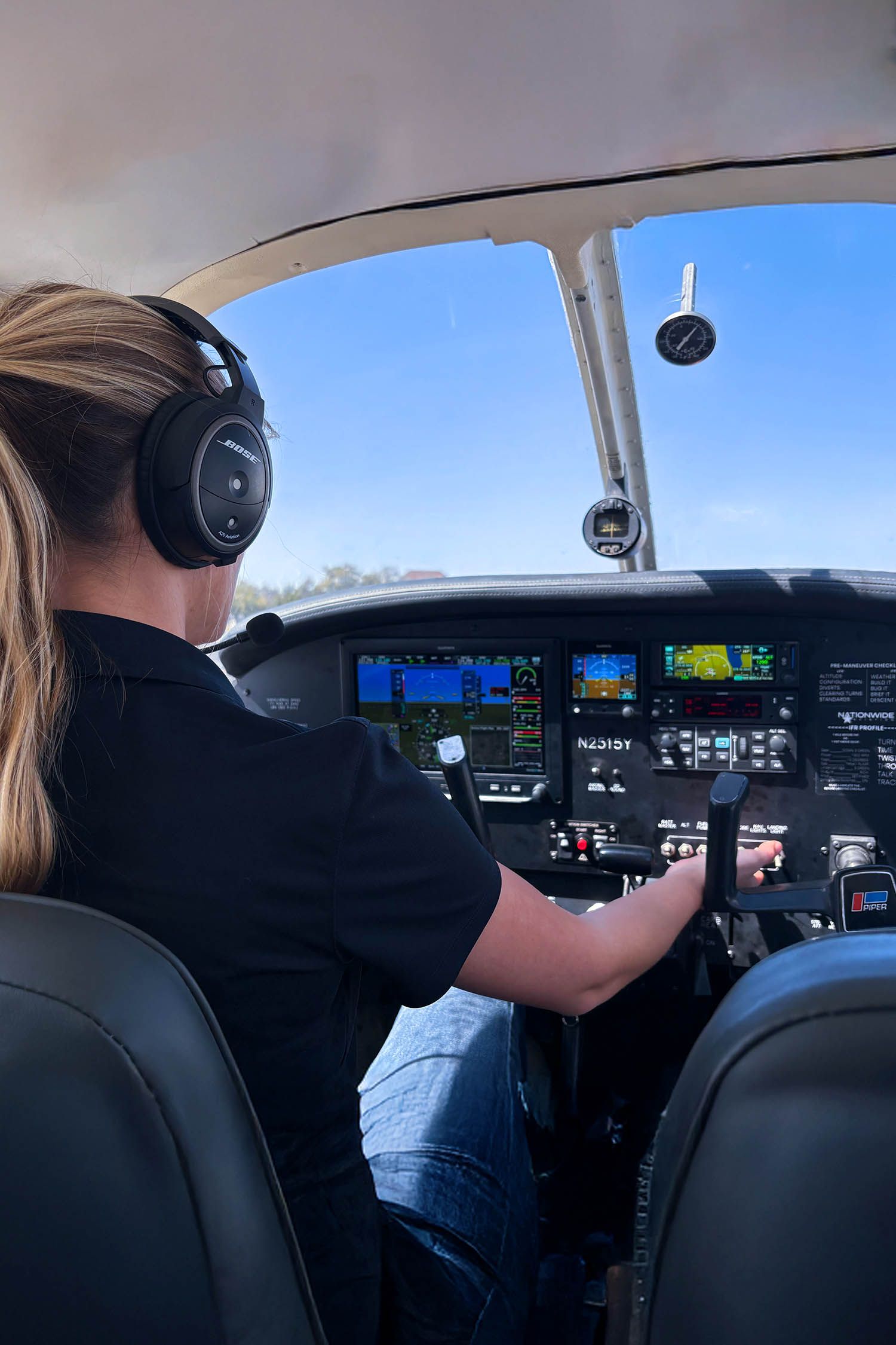 Student pilot wearing headset inside cockpit during training flight.