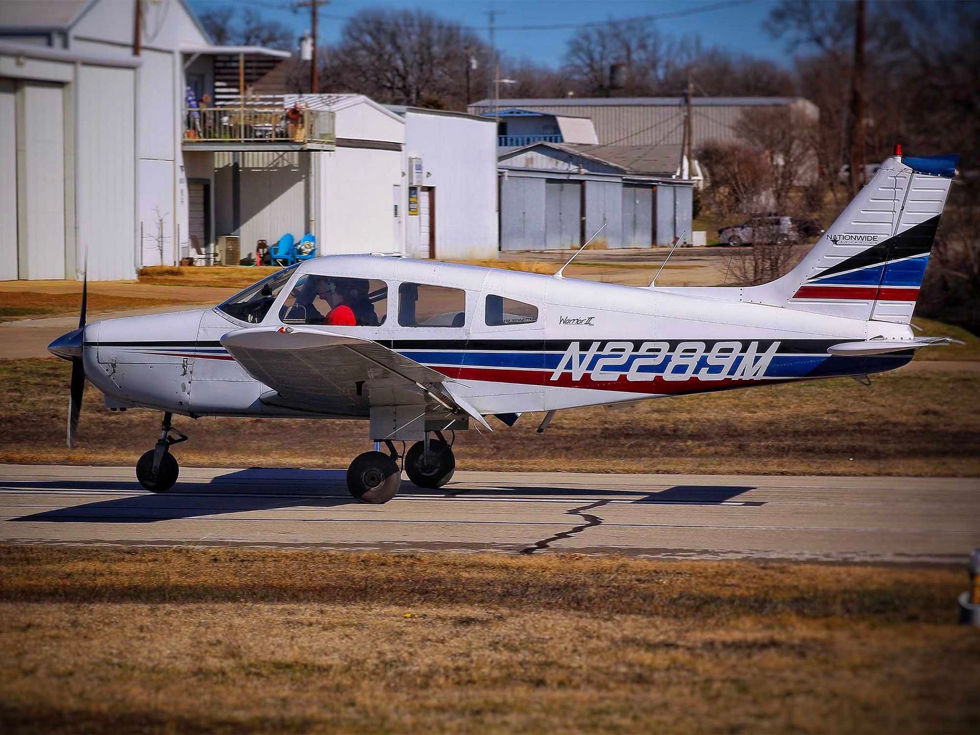 Single-engine training aircraft parked outdoors near the hangar.