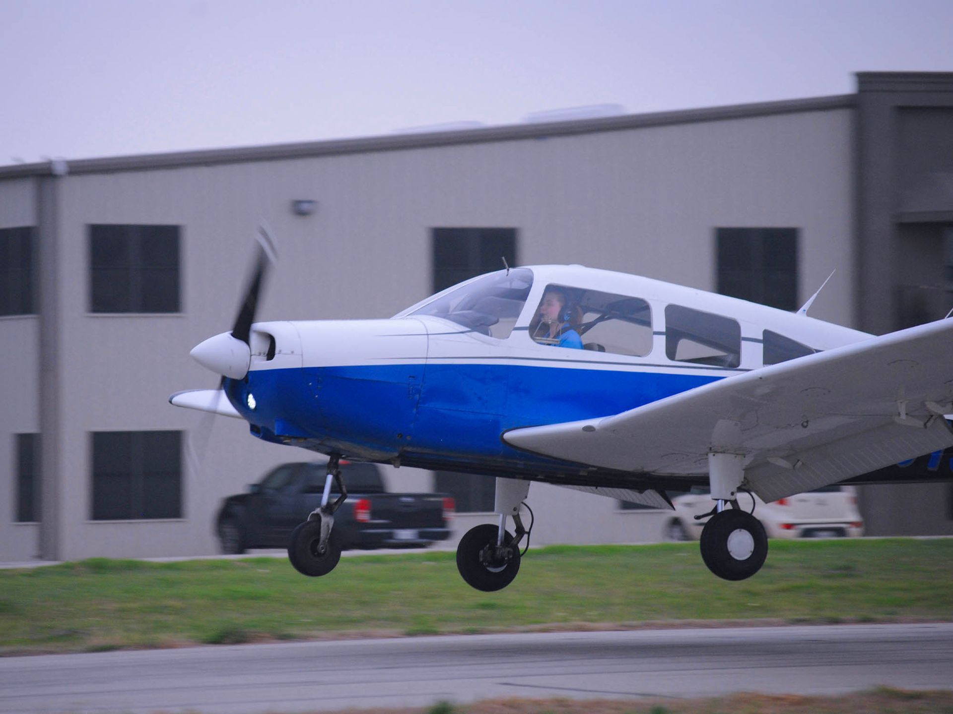 Blue and white single-engine aircraft parked outside the training facility.