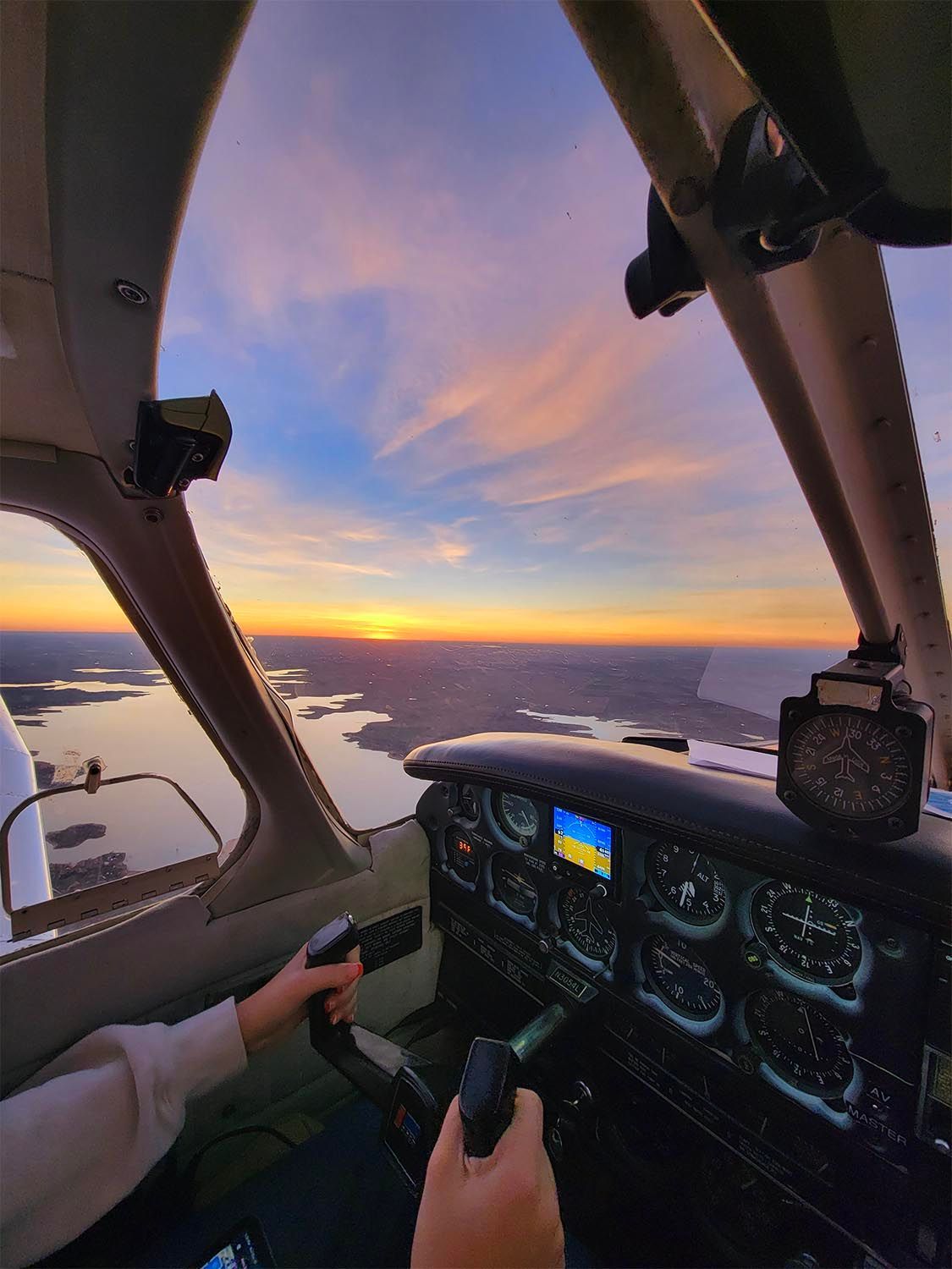 Sunset view captured beneath an aircraft wing during an evening training flight.