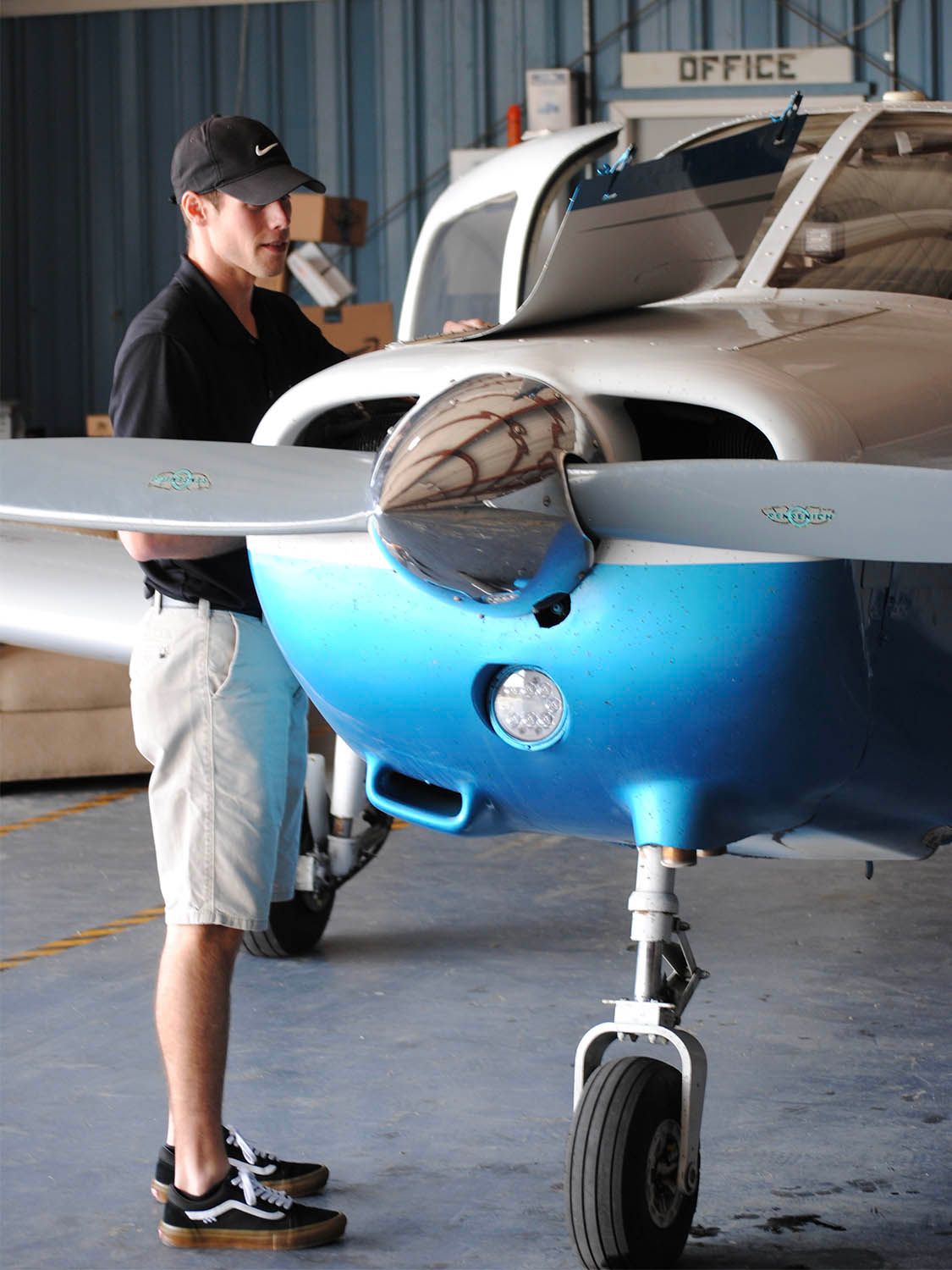 Aircraft technician inspecting engine components inside hangar.