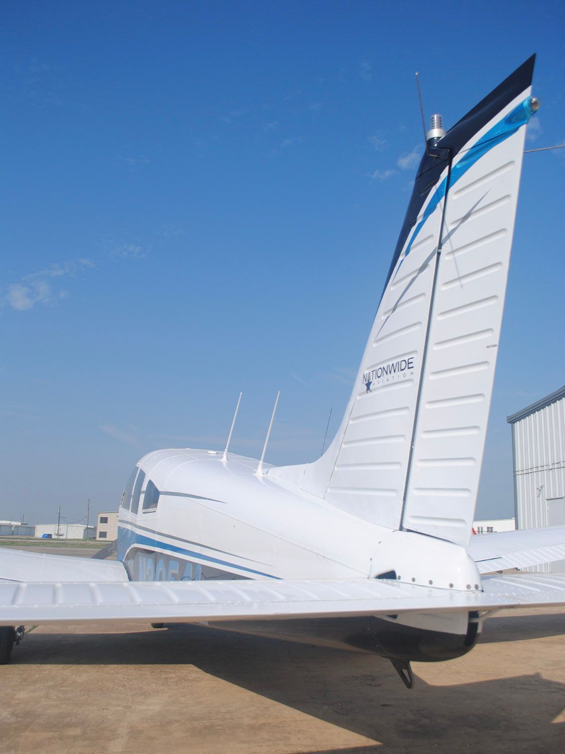 Aircraft tail vertical stabilizer against a clear blue sky.