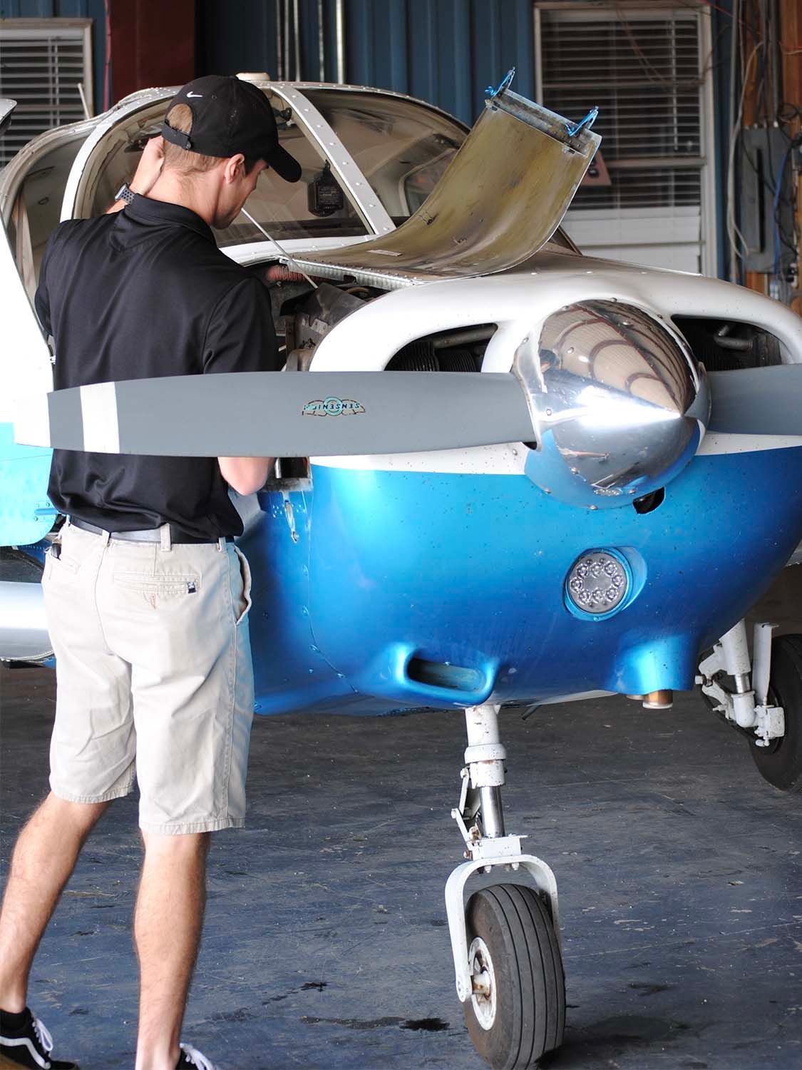 Aircraft mechanic inspecting engine components during maintenance.