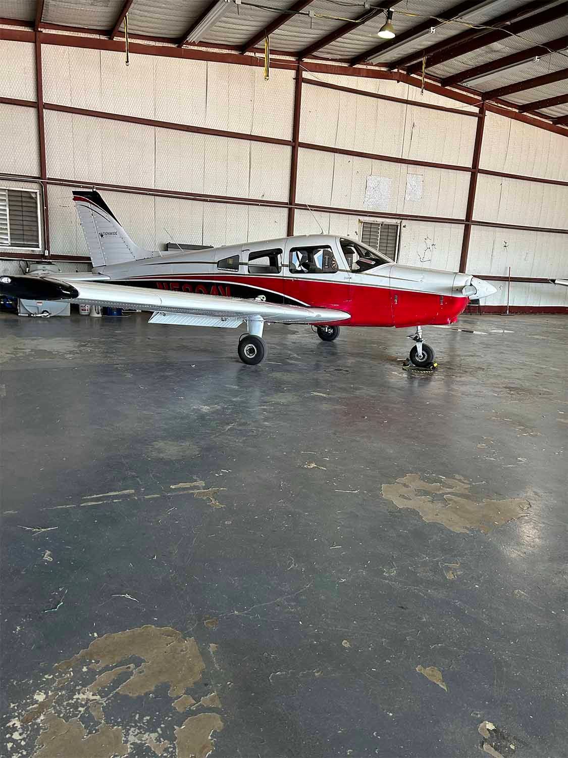 Single-engine aircraft parked inside a hangar during routine storage.