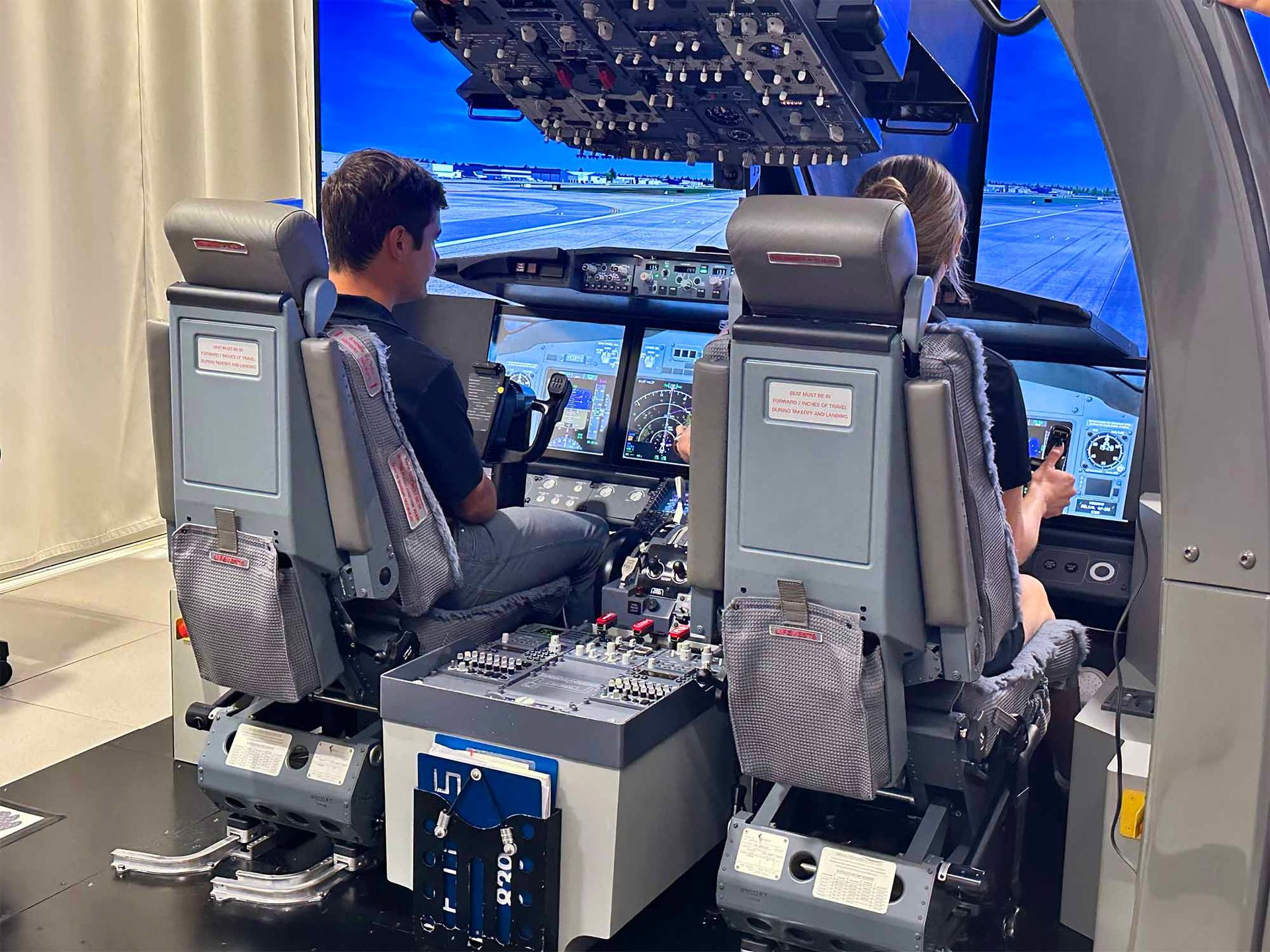 Students training inside a full-flight simulator with panoramic display.