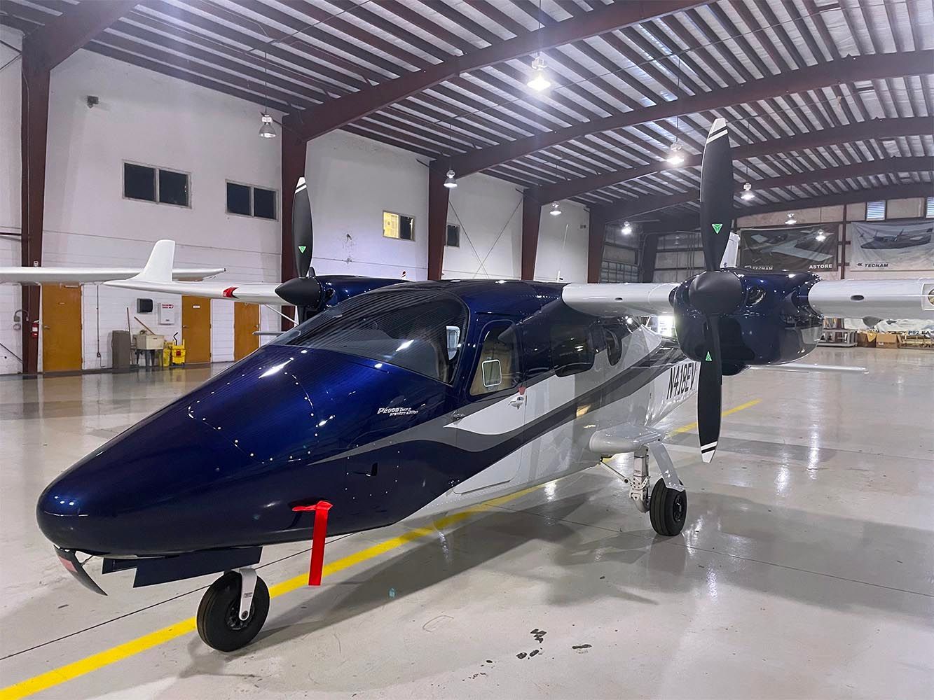Dark blue twin-engine aircraft parked inside a spacious hangar.