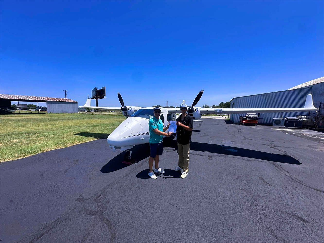Twin-engine training aircraft parked on the ramp under clear blue skies.