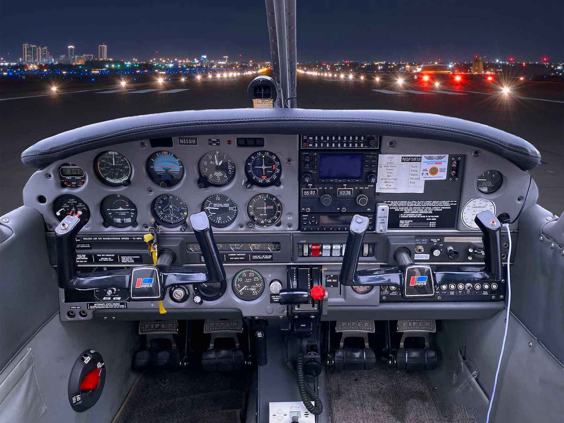 Nighttime cockpit view with illuminated flight instruments on the runway.