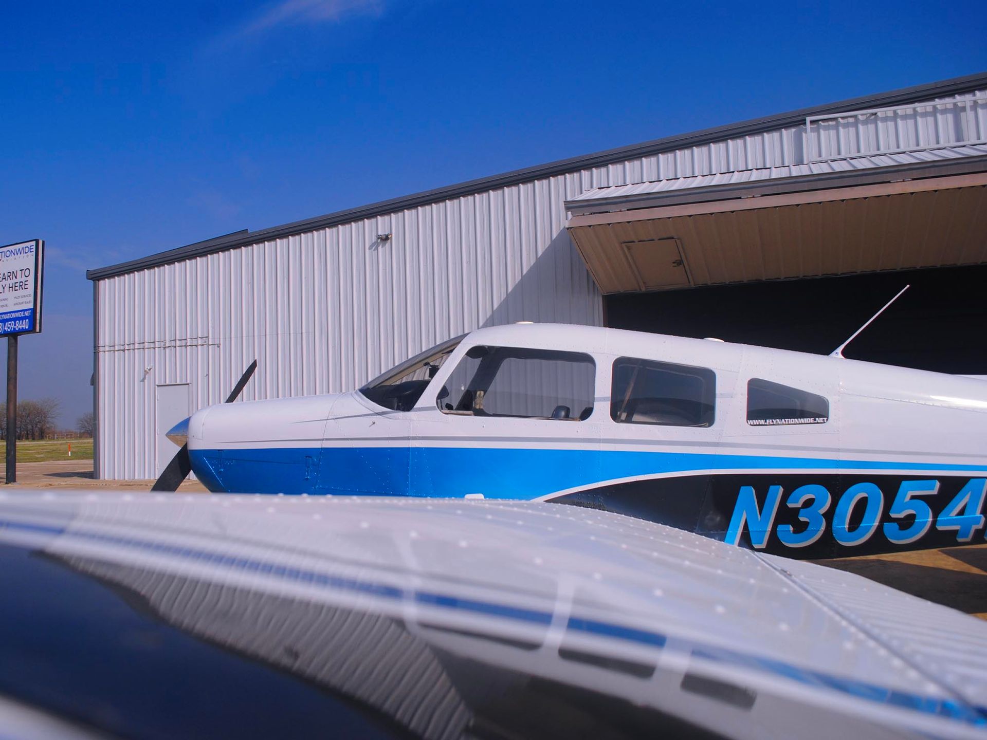 Aircraft parked outside the hangar on a sunny day.