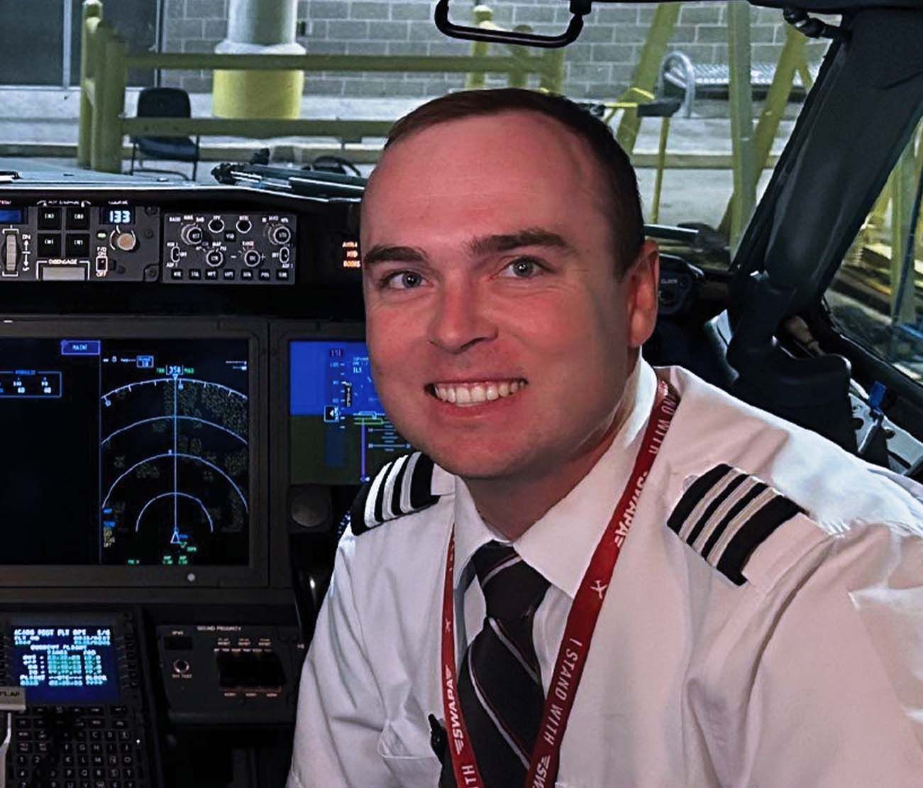Student pilot smiling inside flight simulator for testimonial.