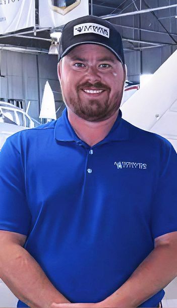 Man smiling inside aircraft hangar for aviation team portrait.