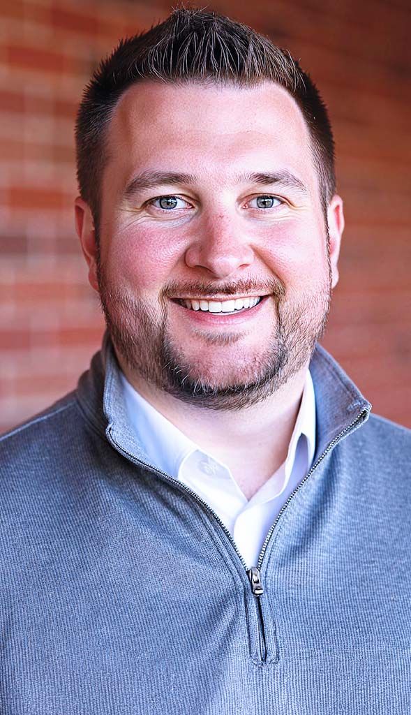 Smiling man standing outdoors for aviation team portrait.