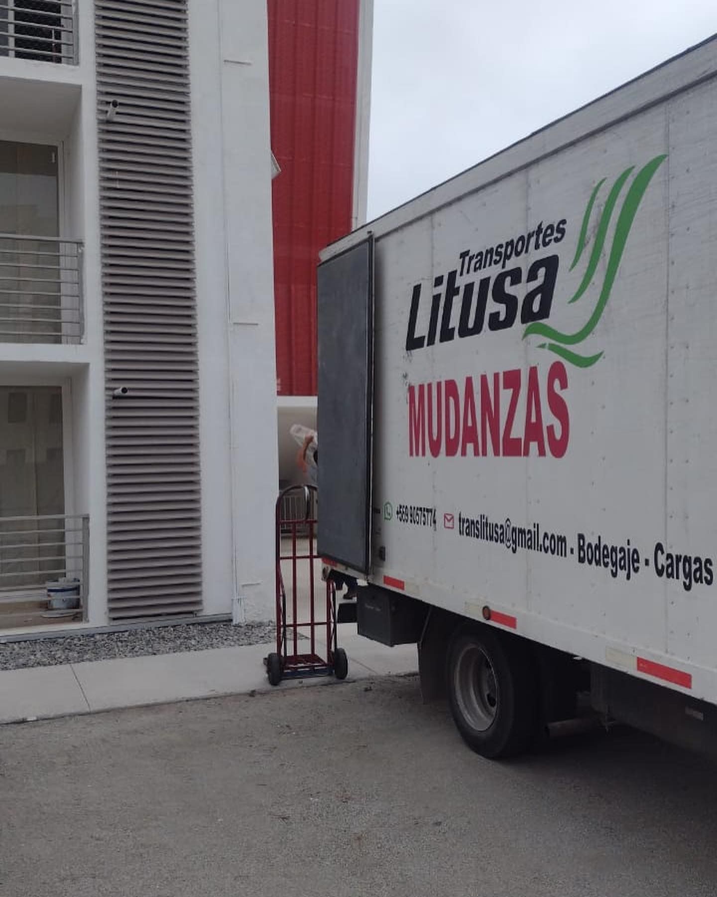 Camión de mudanzas cargando junto a un edificio. El camión tiene el logo de 