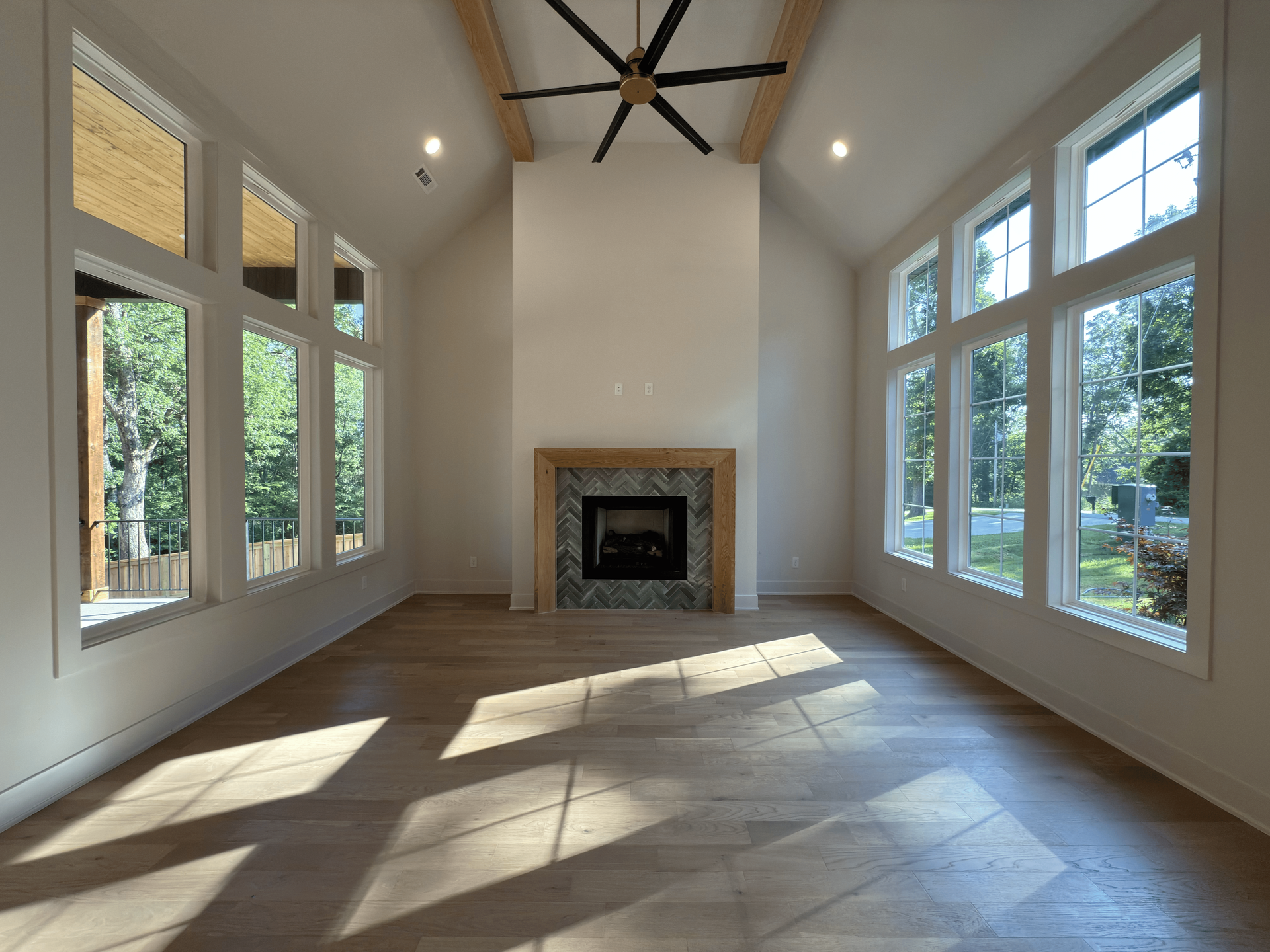 Living room with a grand piano, stone fireplace, and light-colored furniture.