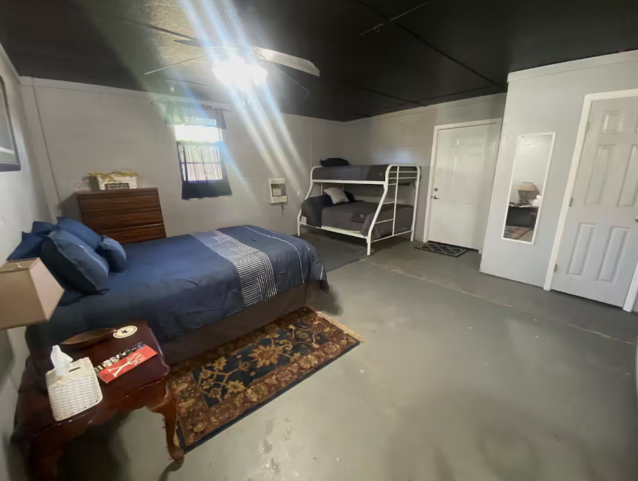 A bedroom with a bed , bunk bed , nightstand and dresser.