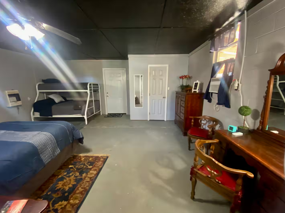 A bedroom with two beds , a dresser , a chair and a mirror.