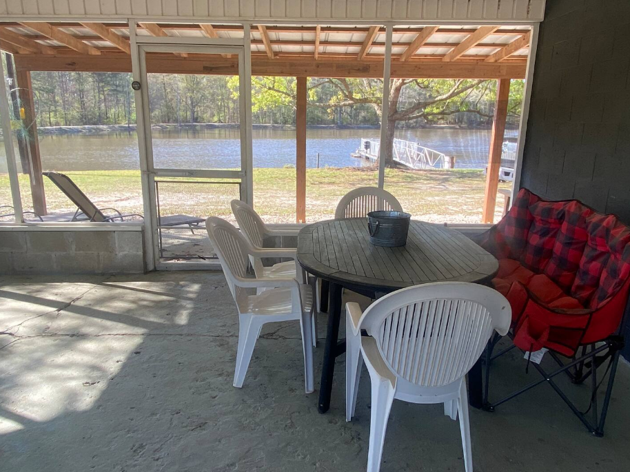 A screened in porch with a table and chairs and a bench.