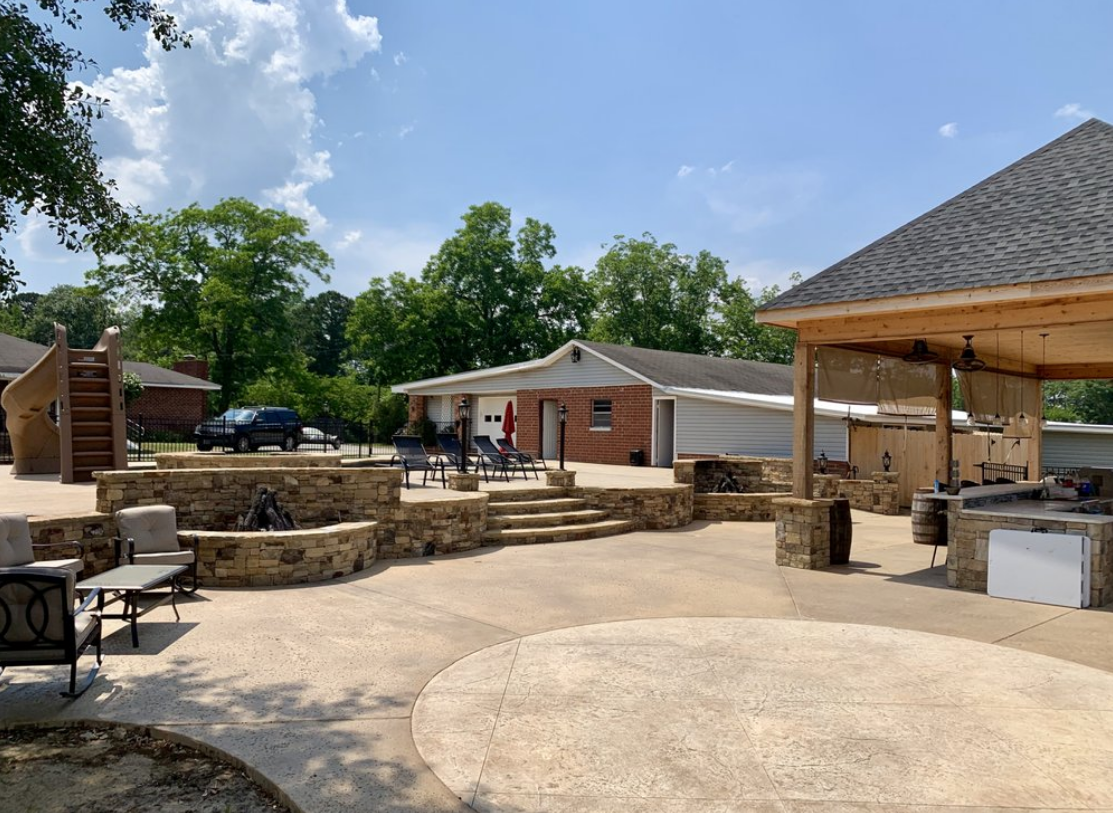 A large patio area with a gazebo and a brick house in the background.