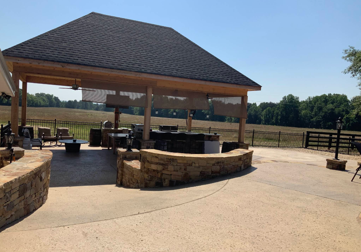 A pavilion with a fire pit and a fence in the background