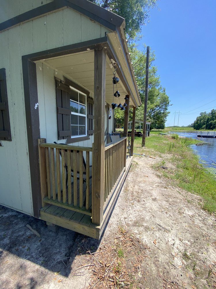 A small house with a porch next to a body of water.