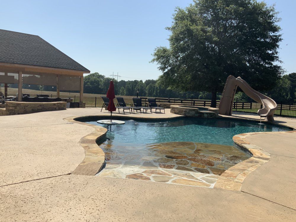 A large swimming pool with a slide and chairs around it