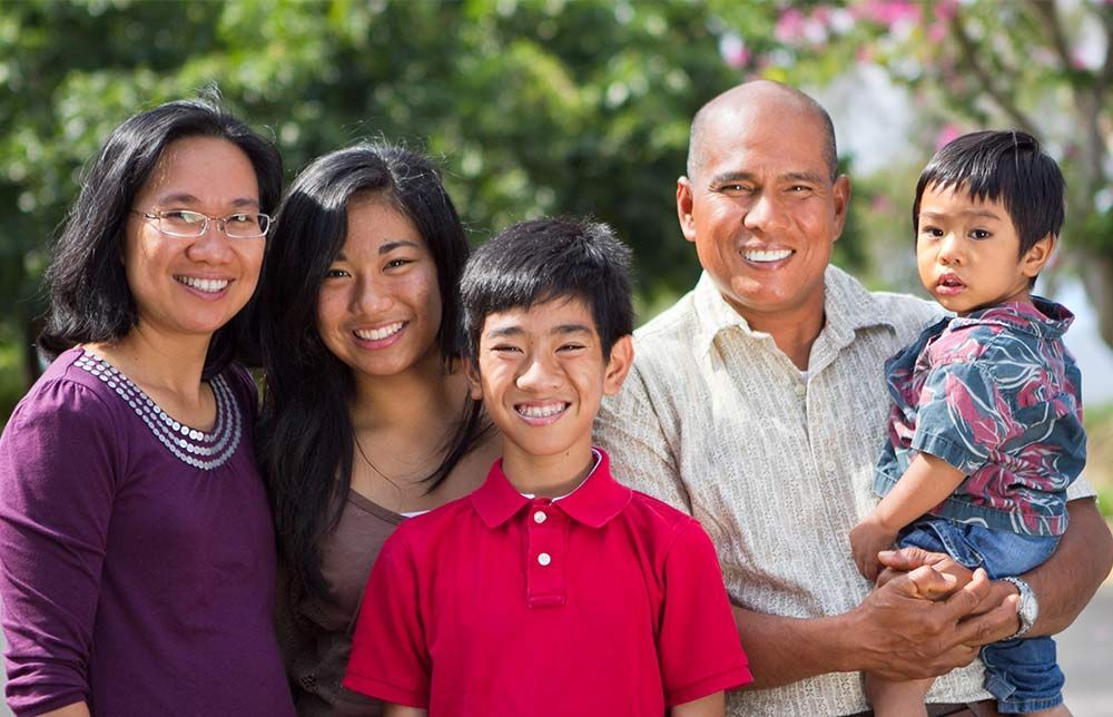 Family of five smiling outdoors.