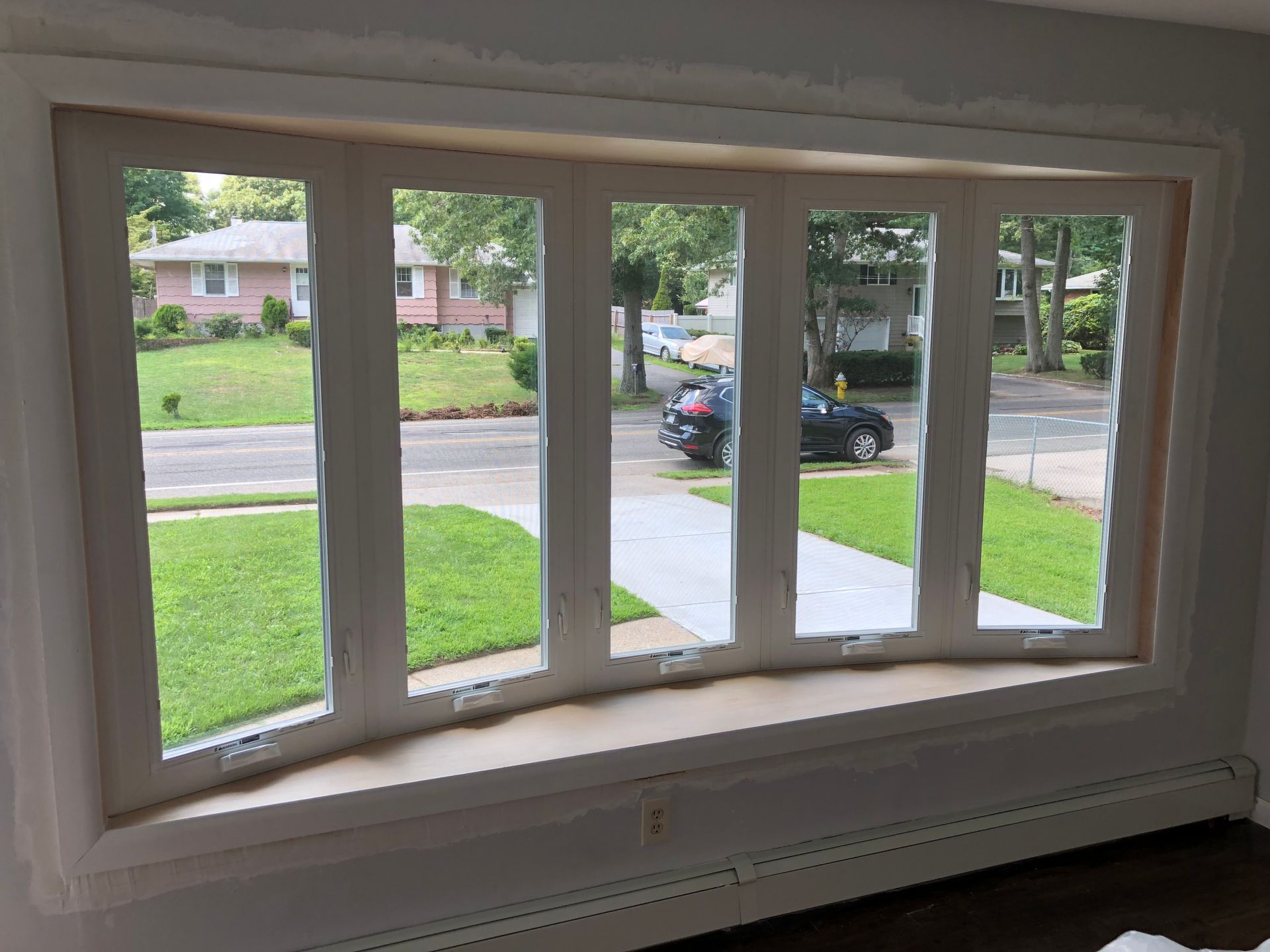 A large window in a living room with a view of a street.