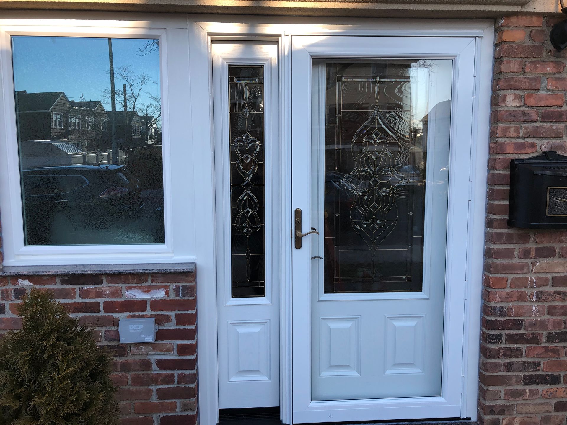 A white door is sitting on a brick wall next to a window.
