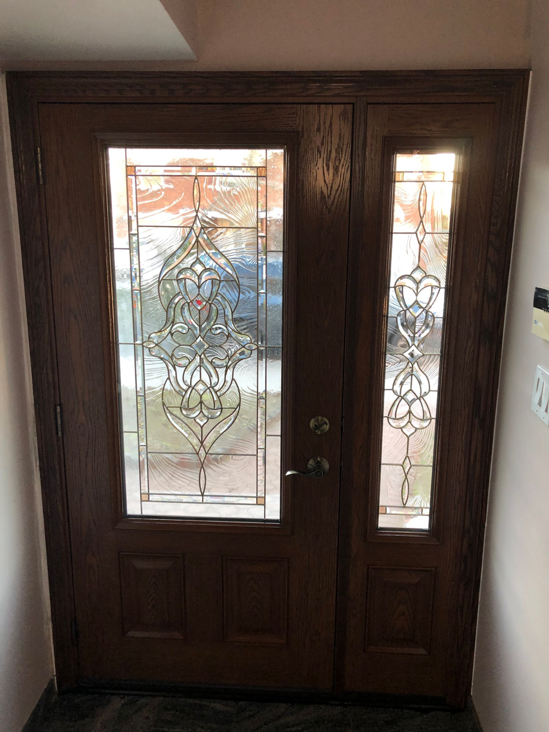 A wooden door with a stained glass window in a hallway.