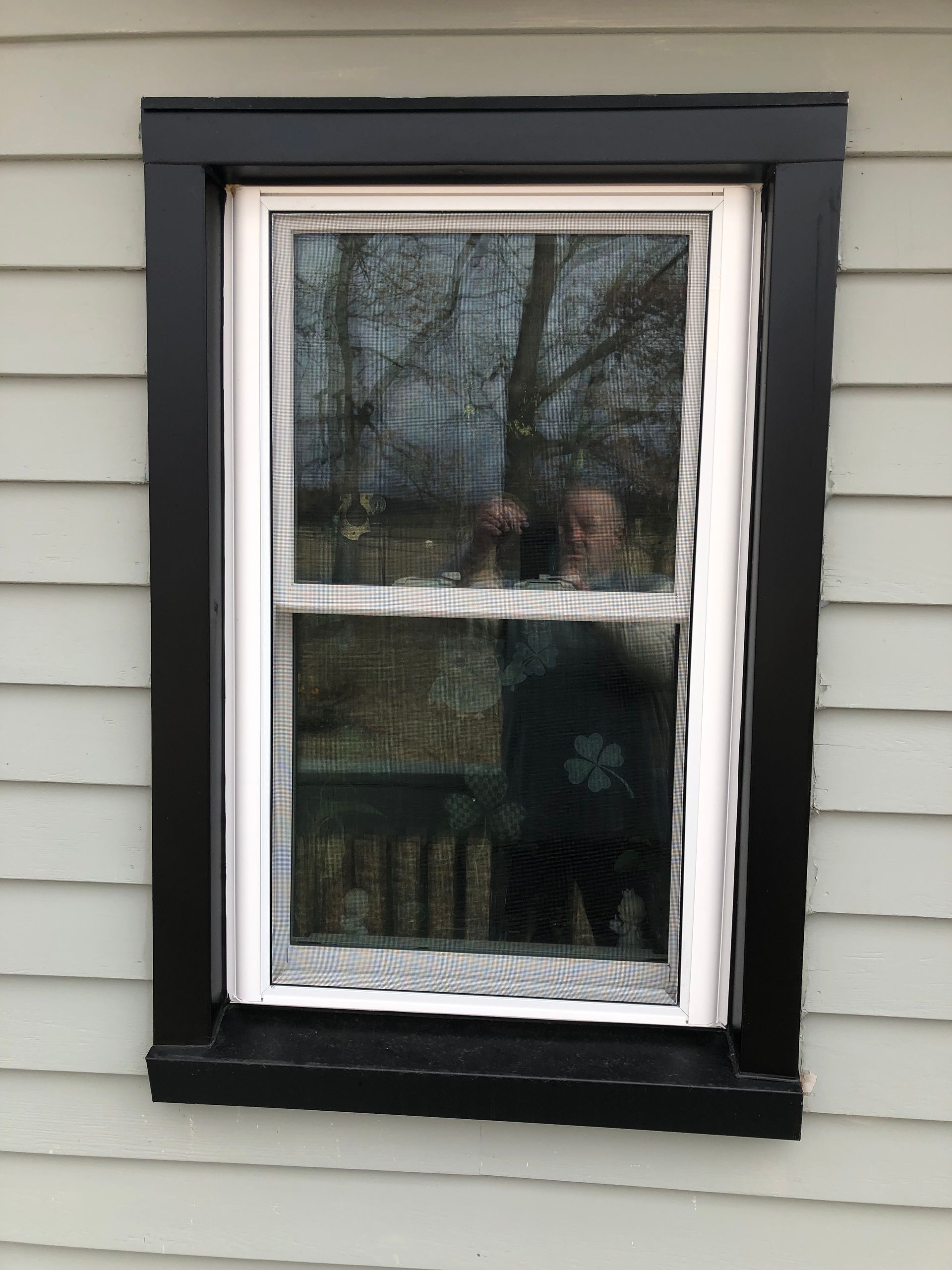 A window on the side of a house with a black frame