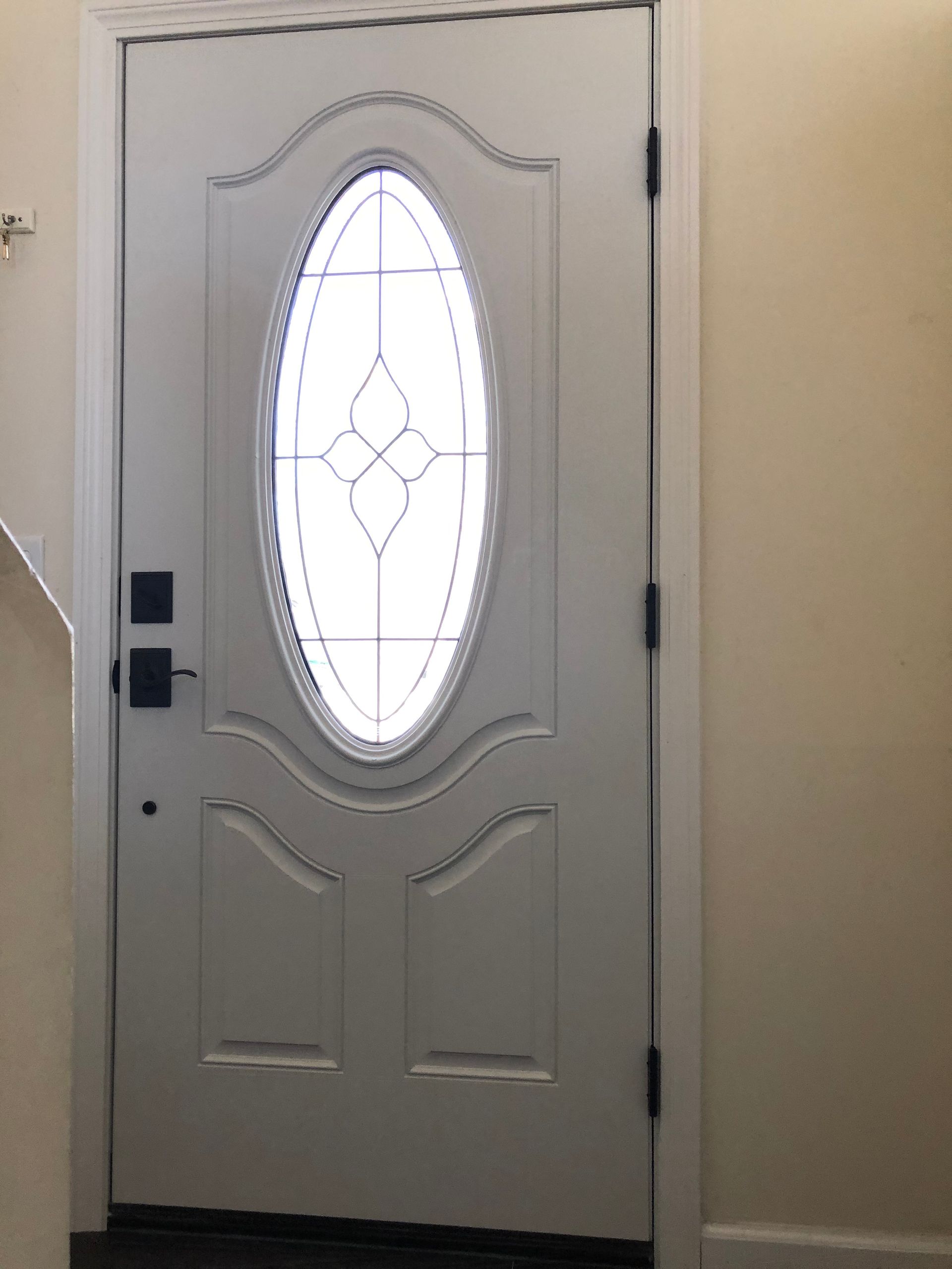 A white door with a stained glass window in a hallway.