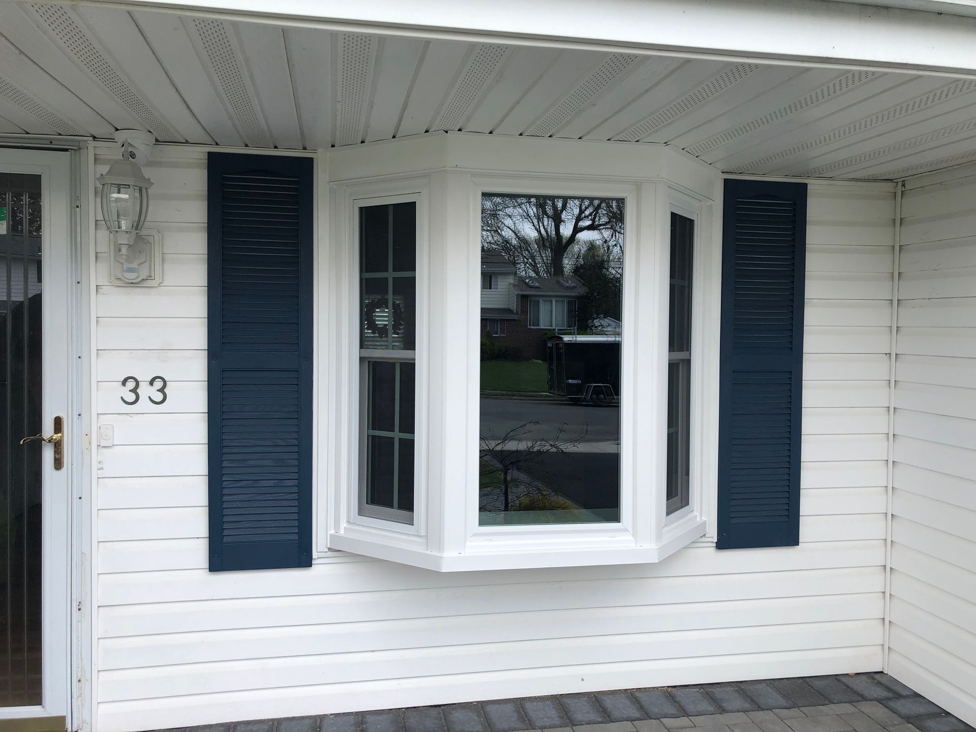 A white house with a bay window and blue shutters