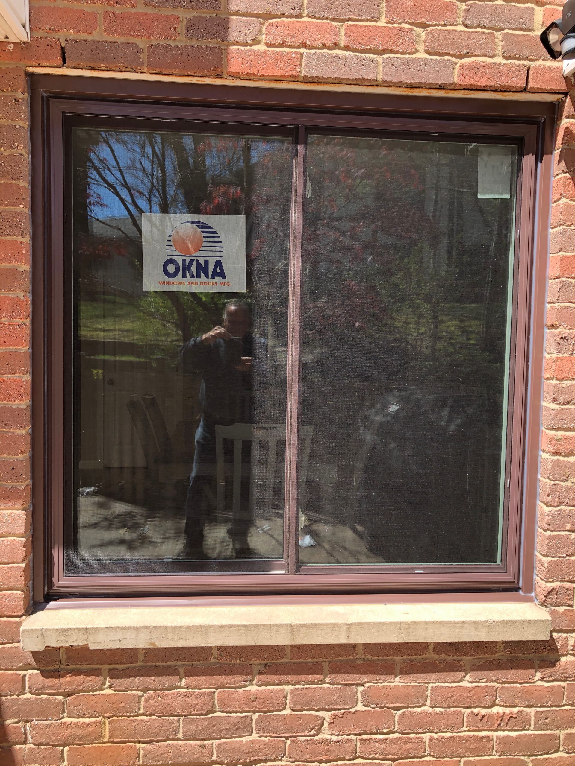 A window on a brick wall with a sign that says okma on it.