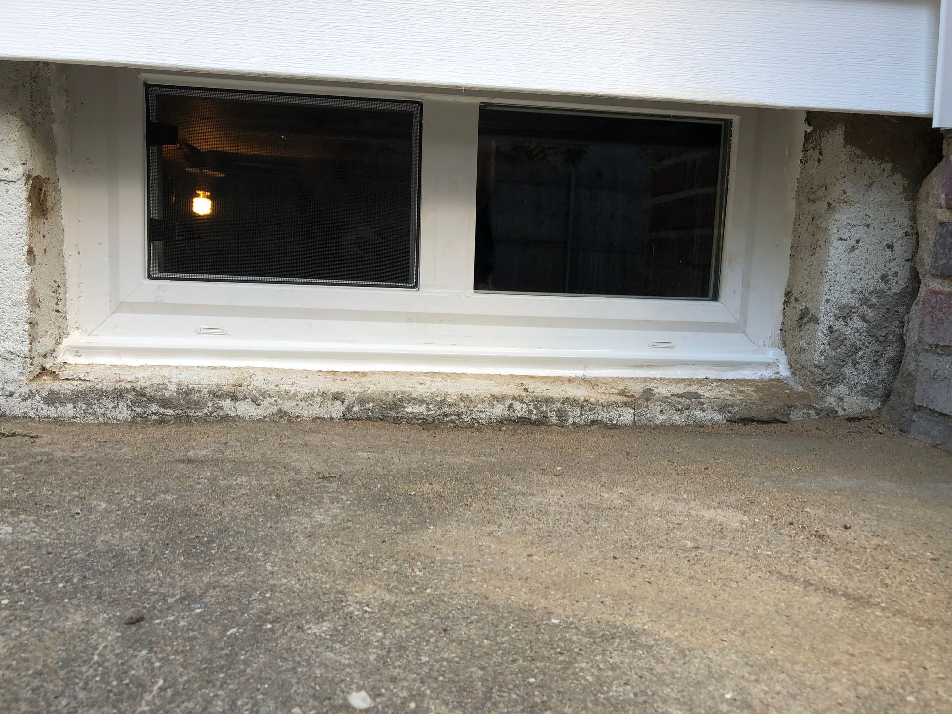 A window in a basement with a light coming out of it.