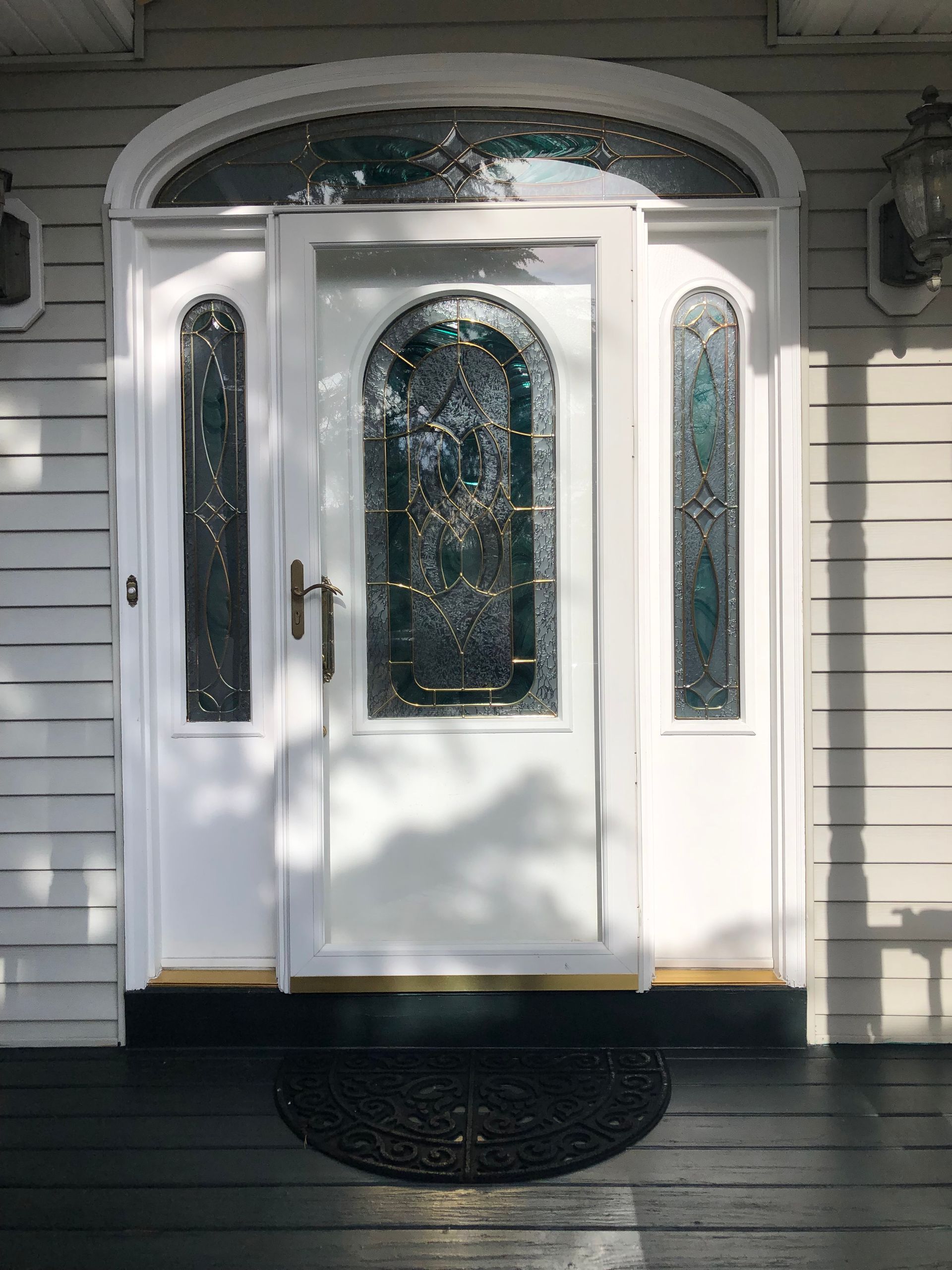 A white door with stained glass windows is on the front of a house.