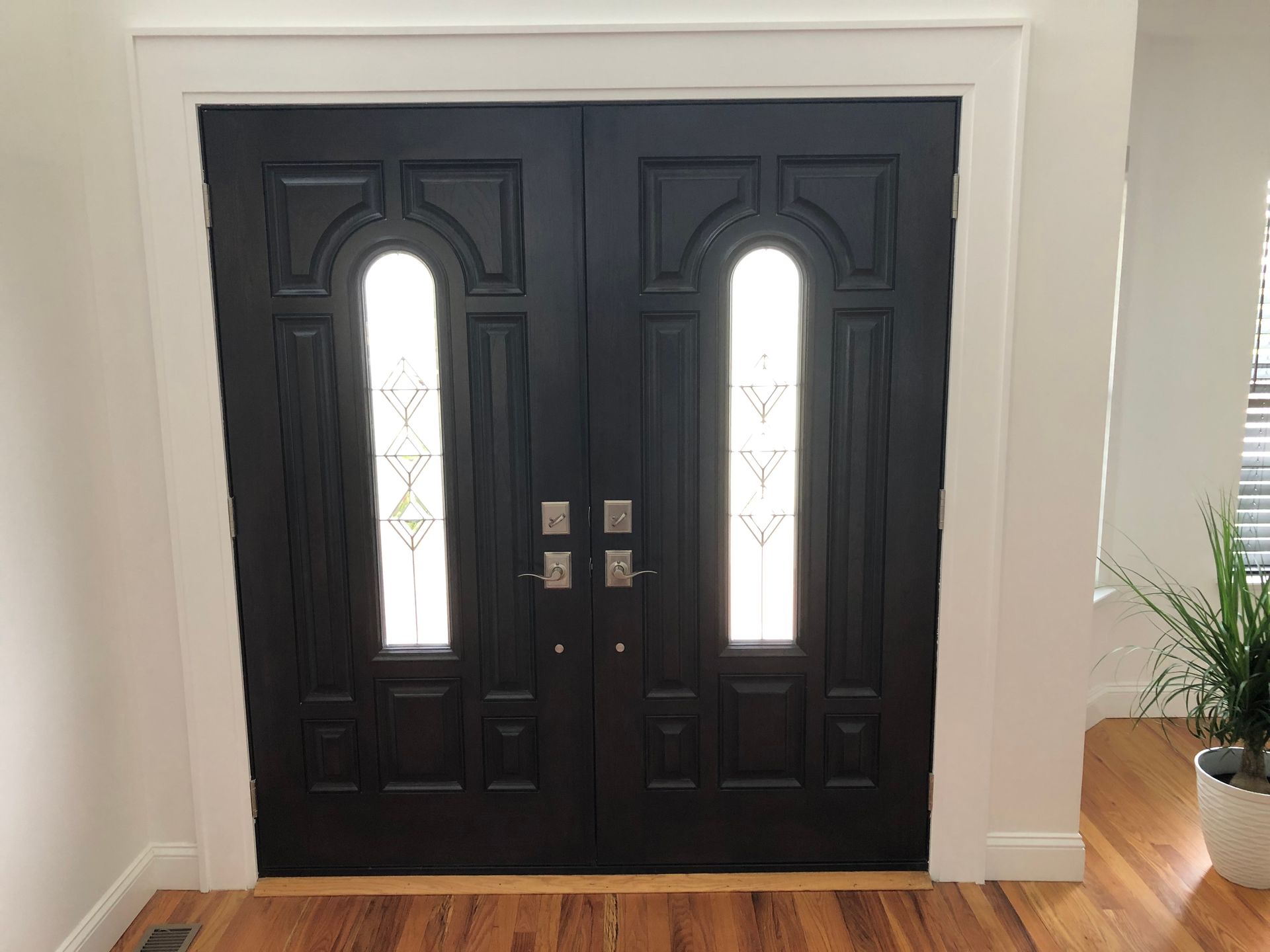 A pair of black doors with two windows in a hallway.