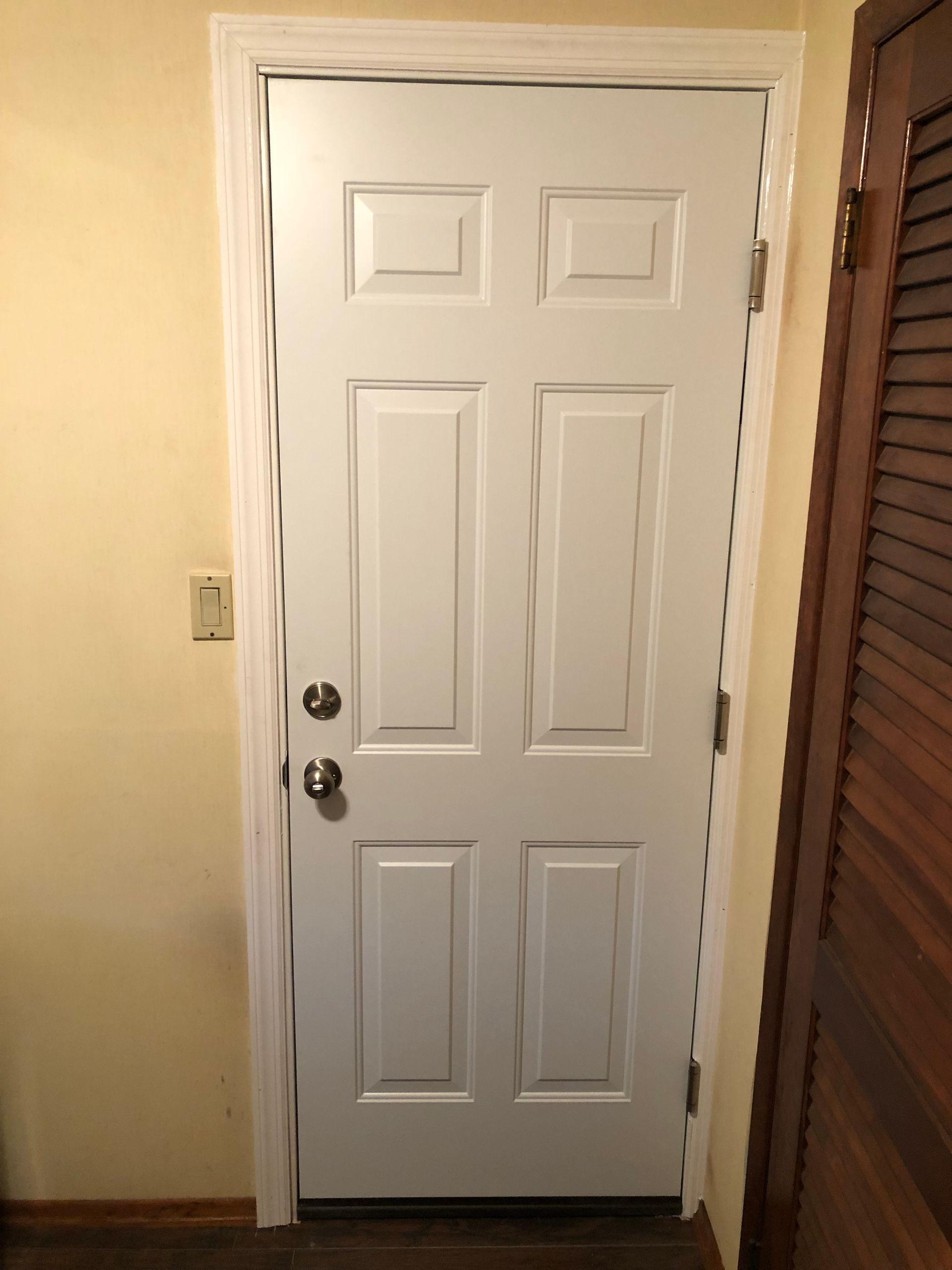 A white door is sitting in a hallway next to a closet.