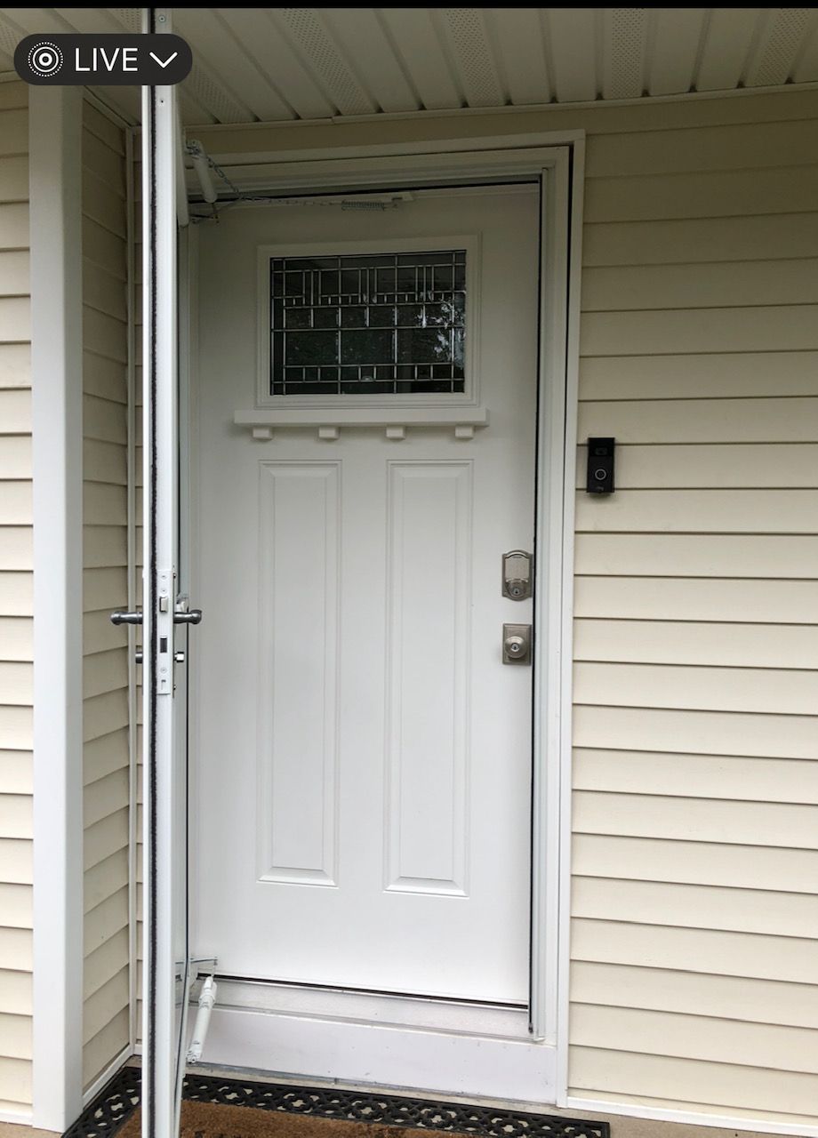 A white door with a stained glass window is open on a house.