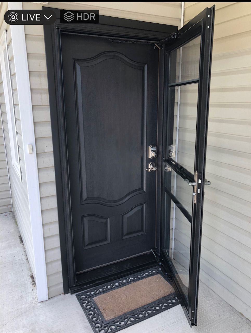 A black door with a door mat in front of it