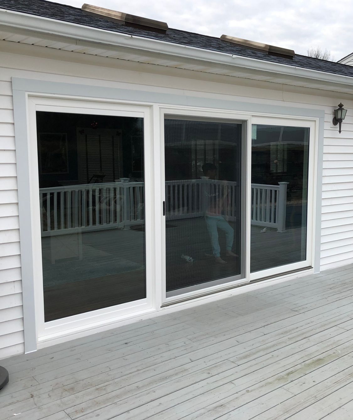 A white house with a deck and sliding glass doors.
