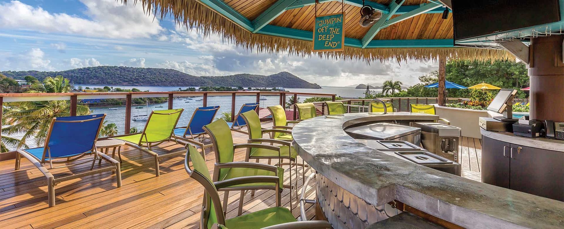 A beach bar with chairs and umbrellas overlooking a body of water.