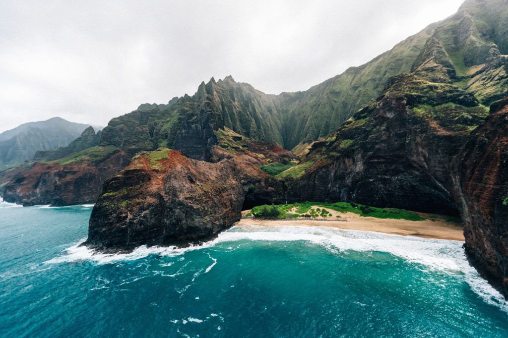 An aerial view of a beach surrounded by mountains and a body of water.