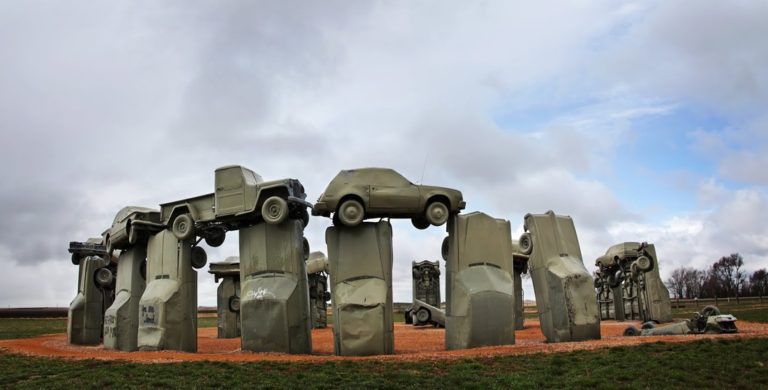 A statue of cars sitting on top of rocks in a field.