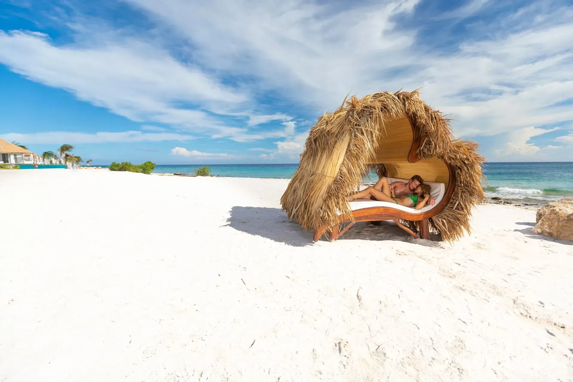 A woman is laying in a hut on the beach.