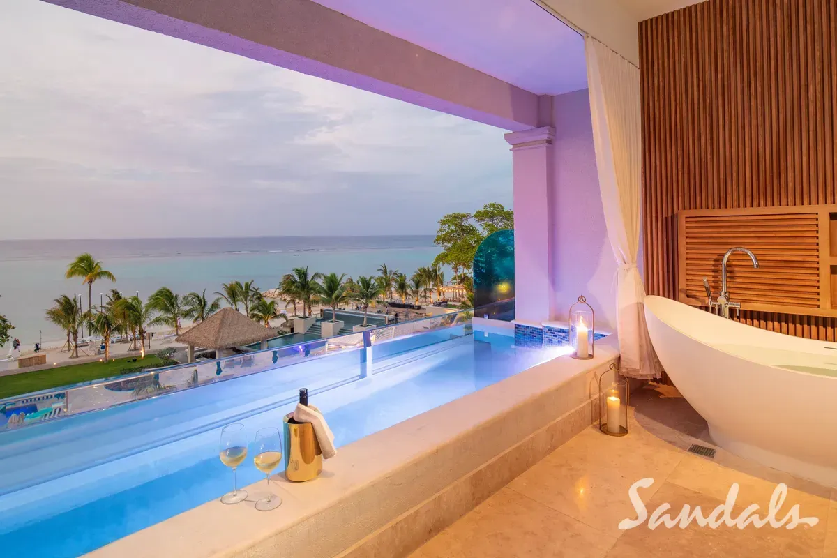 A bathtub with a view of a swimming pool and the ocean.