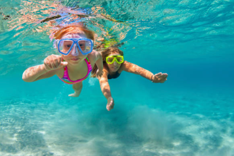 Two people are swimming underwater in the ocean.