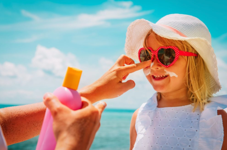 A woman is applying sunscreen to a little girl 's nose.