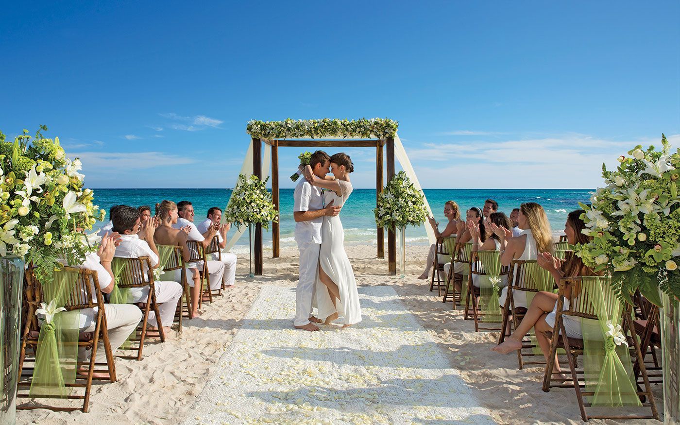 A bride and groom are dancing during their wedding ceremony on the beach.