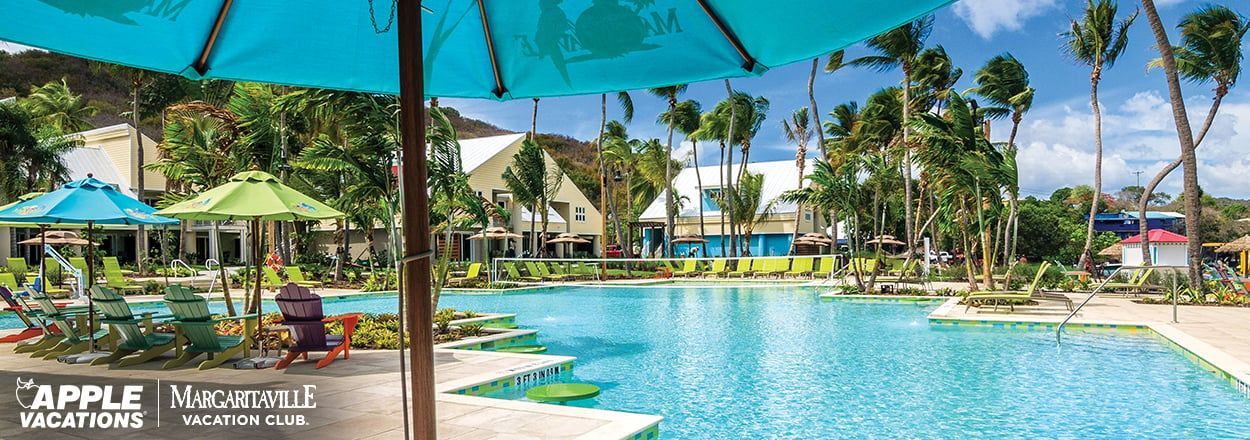 A large swimming pool surrounded by palm trees and umbrellas